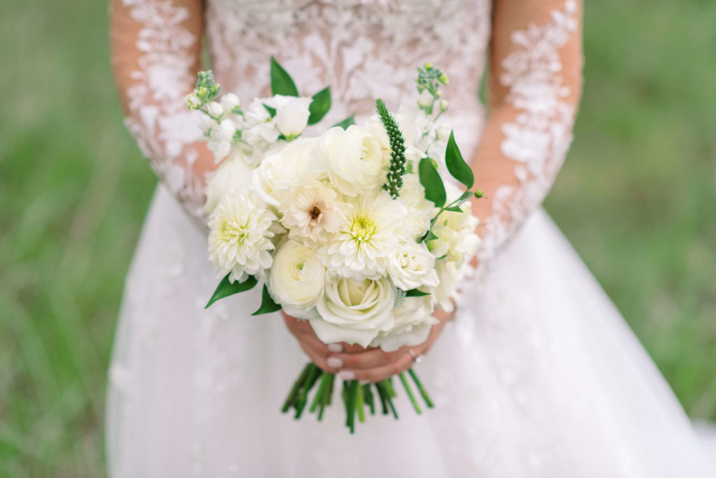 Bride holding bouquet of white roses and flowers made by Privé Events