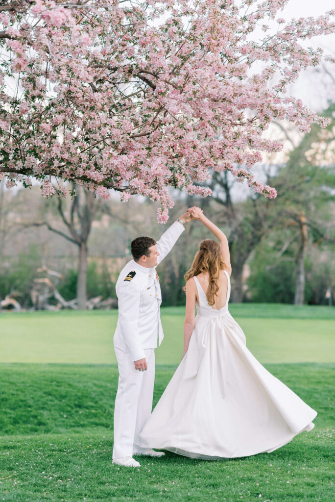 A military officer dances with his new wife under a pink flowering tree at their Washington DC Wedding Venue