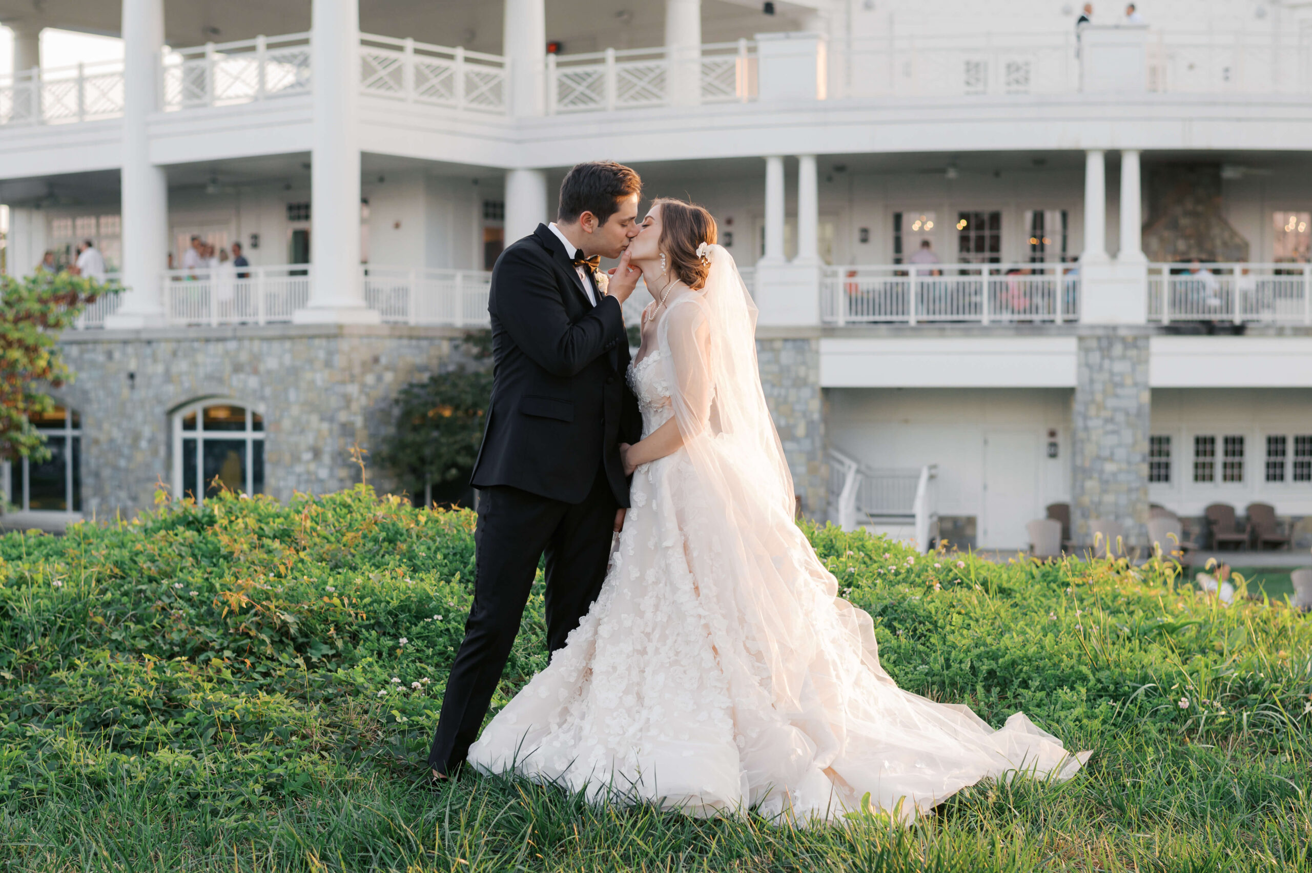 Bride and groom kiss in the sunset outside of the army navy country club during their wedding