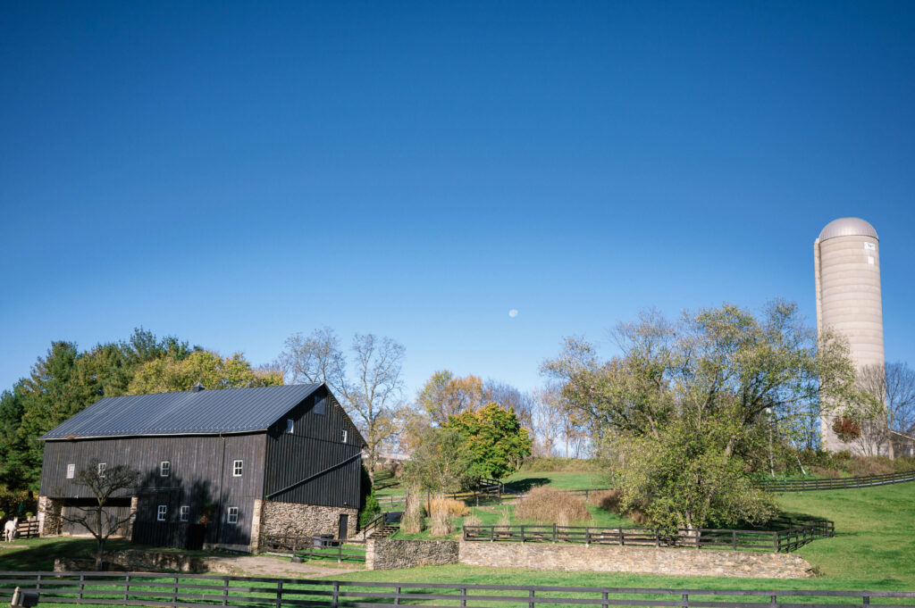 A black barn and tall white silo great guests when they pull up to a Tranquility Farm wedding