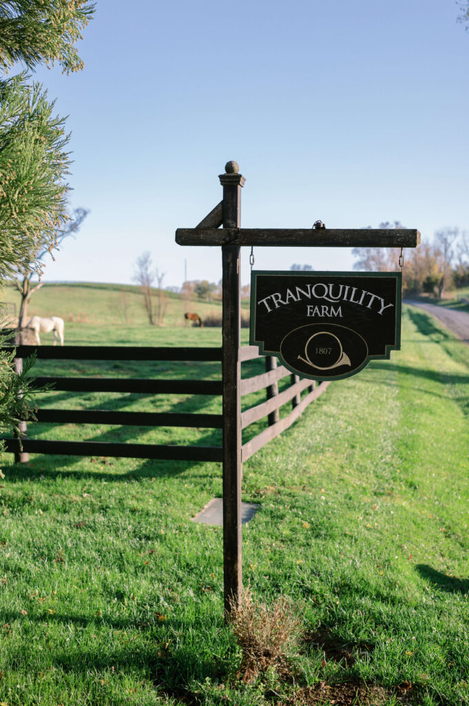 A black Tranquility Farm sign welcomes guests to the wedding venue