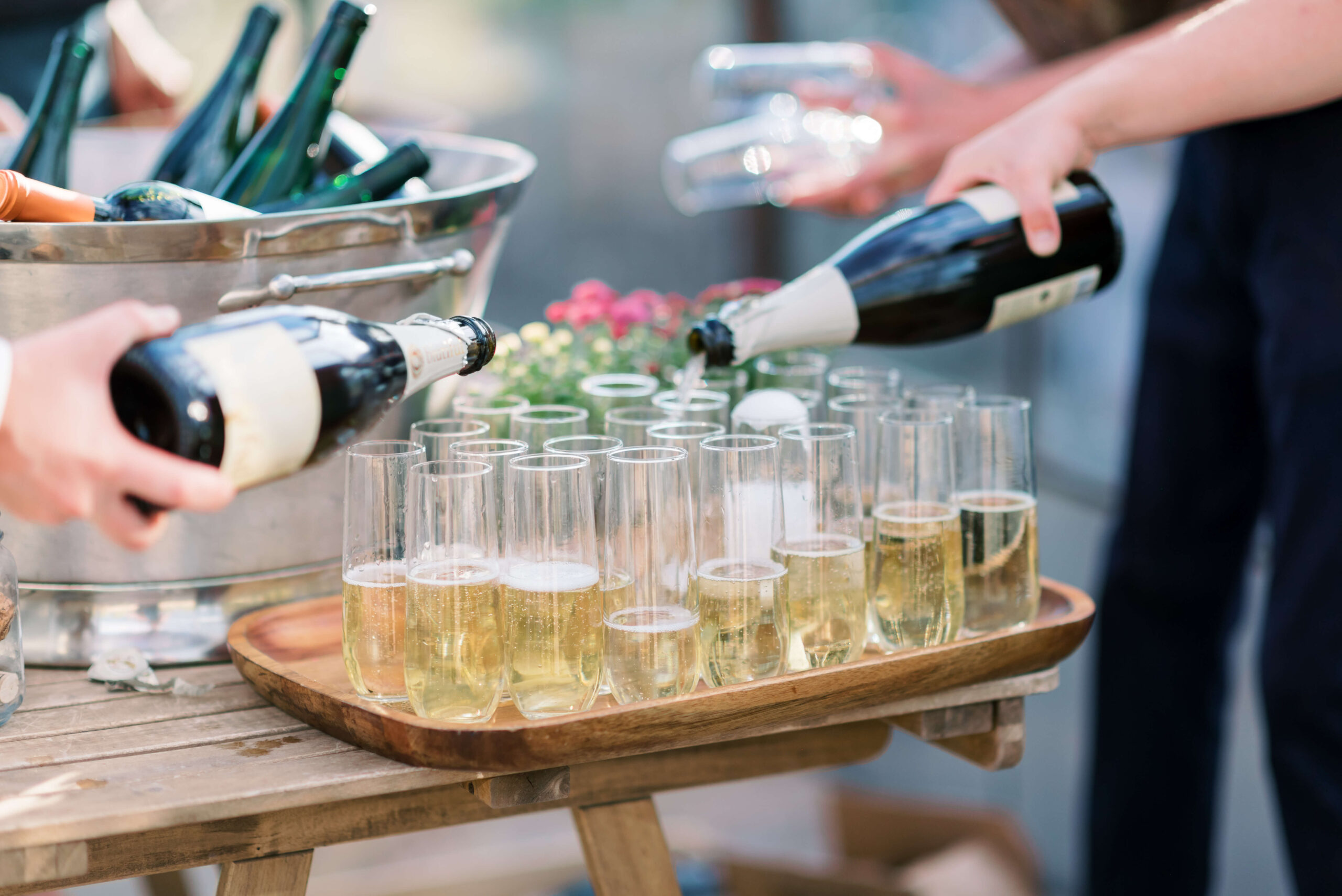 Champagne is poured into flutes while outside at a Stone Tower Wedding