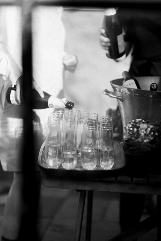 A picture is taken through a window while champagne is poured into flutes at a Stone Tower wedding