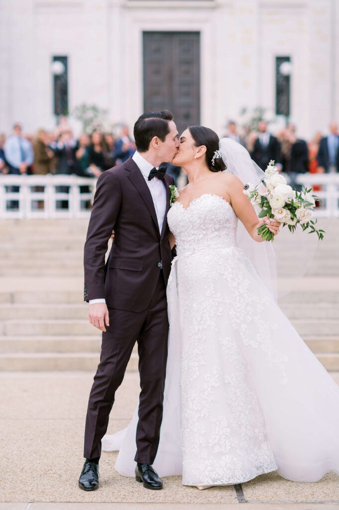 bride and groom kiss on the steps after their wedding