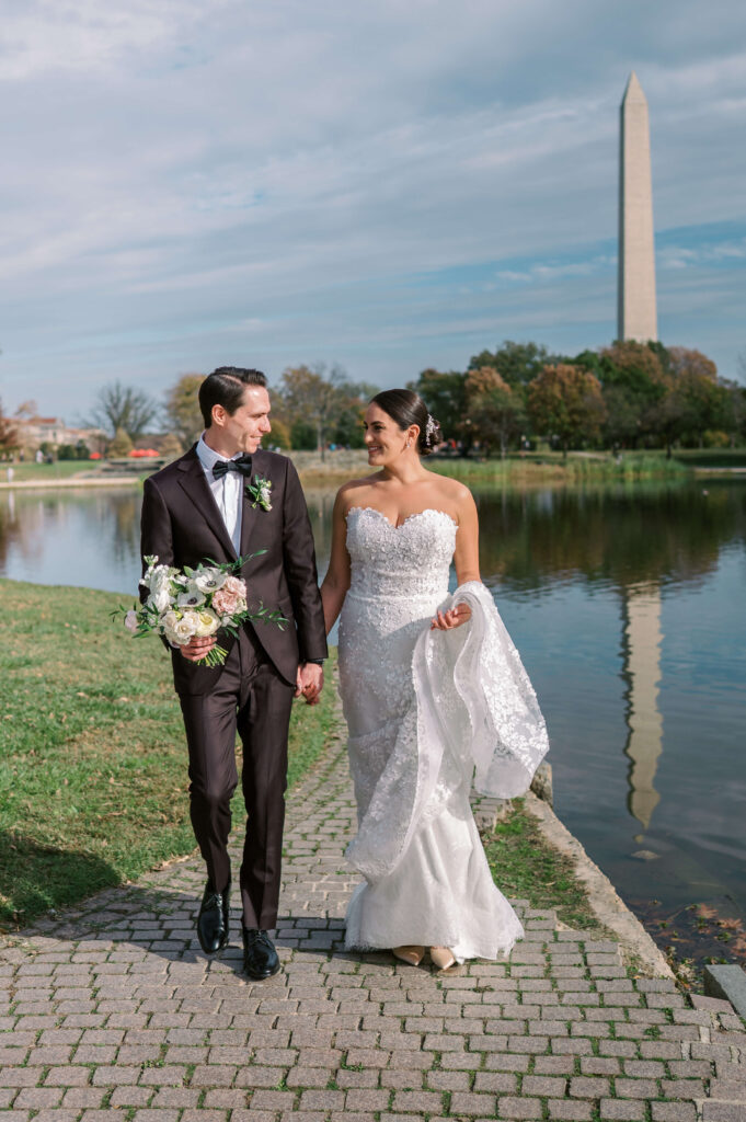 a bride and groom walk together outside of the Washington monument during the portrait session of their potomac view terrace wedding