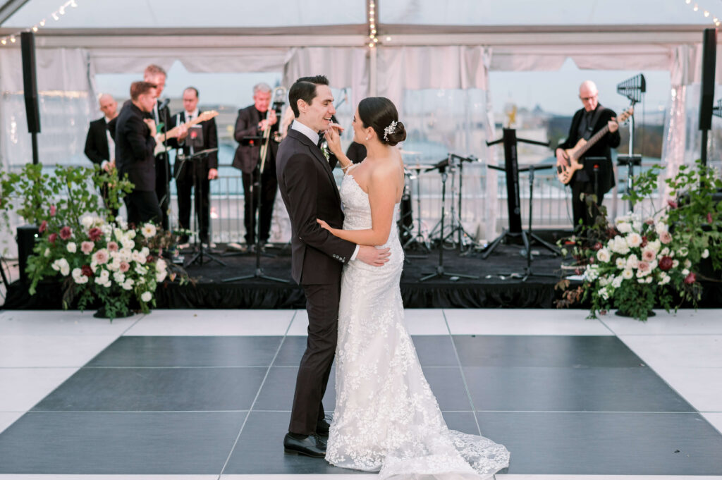 bride in a white dress and groom in a custom suit dance together with a band during their potomac view terrace wedding